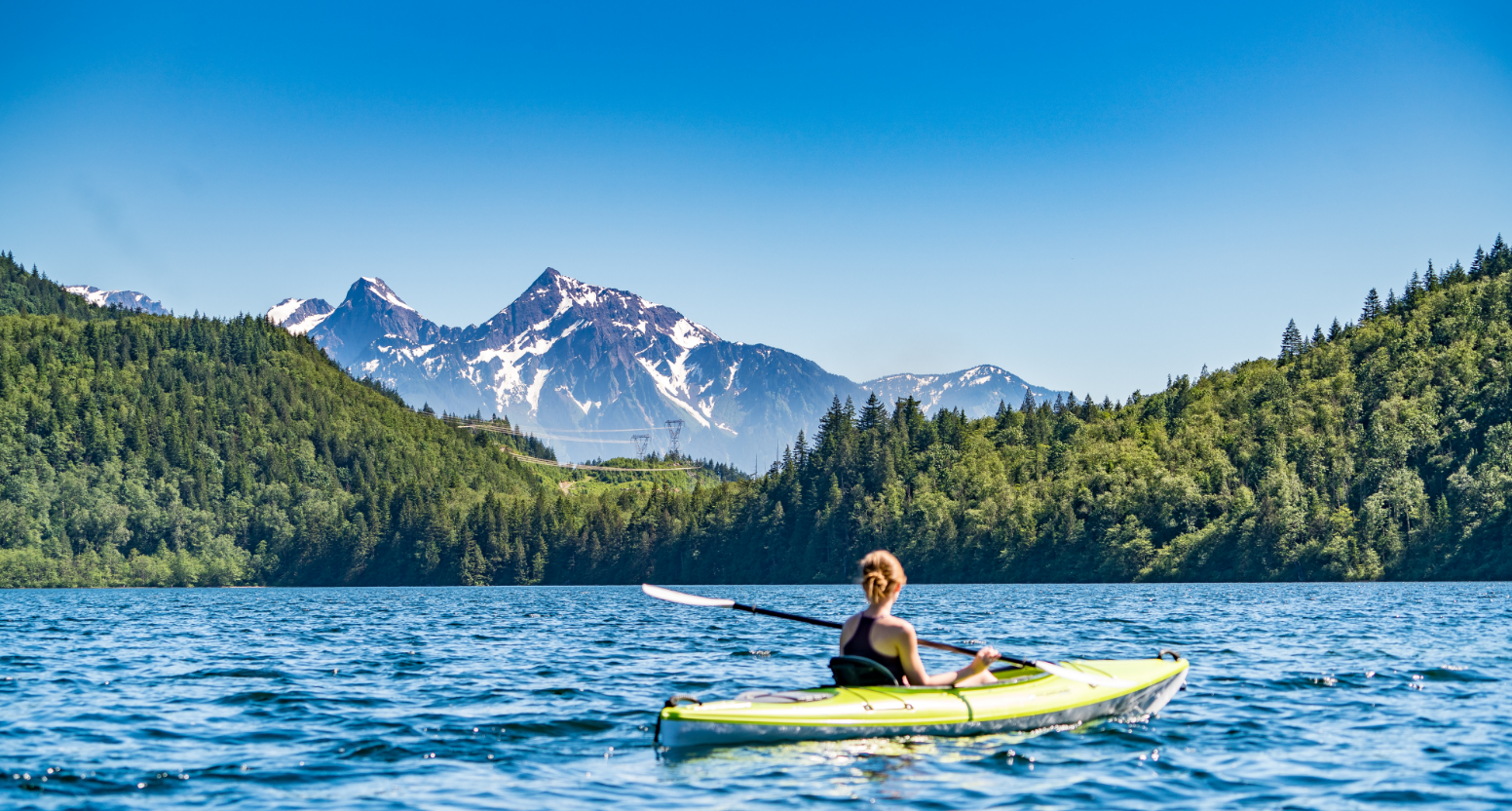 Person kayaking in a lake with mountains in the background